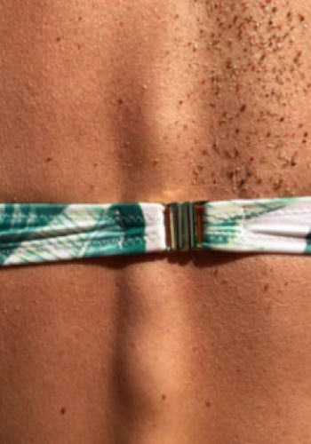 Close-up of a sun-kissed back with freckles and a bikini strap.