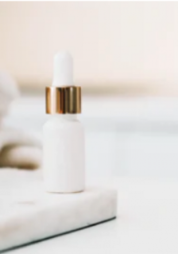 Minimalist white dropper bottle on a marble surface with soft background.